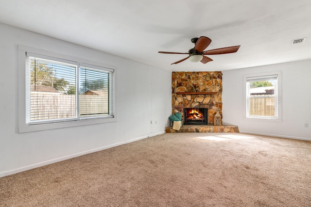 unfurnished living room featuring visible vents, baseboards, a ceiling fan, carpet, and a fireplace