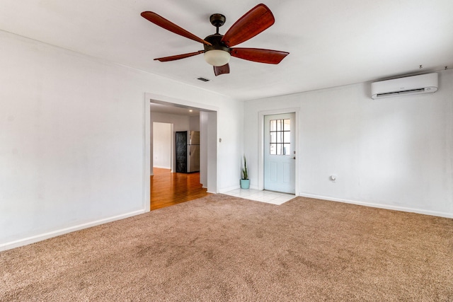 empty room with ceiling fan, a wall mounted air conditioner, baseboards, and light colored carpet