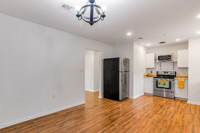 kitchen with light wood-type flooring, visible vents, appliances with stainless steel finishes, and light countertops