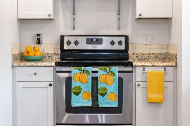 kitchen featuring light stone counters, electric stove, and white cabinetry