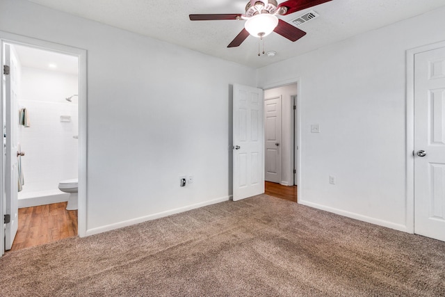 unfurnished bedroom with carpet, visible vents, connected bathroom, a textured ceiling, and baseboards