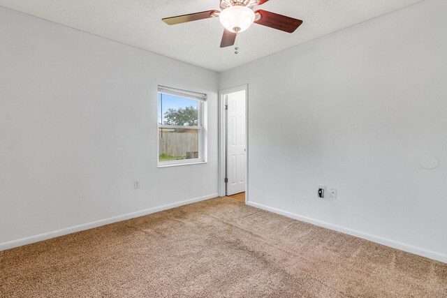 unfurnished room featuring baseboards, a textured ceiling, a ceiling fan, and light colored carpet