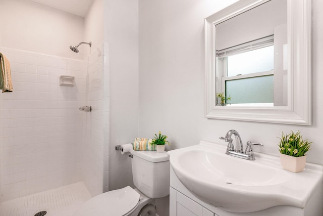 full bathroom with tiled shower, vanity, and toilet