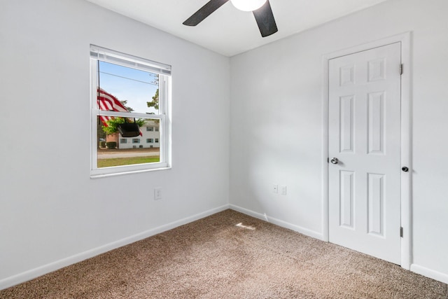 carpeted spare room with ceiling fan and baseboards