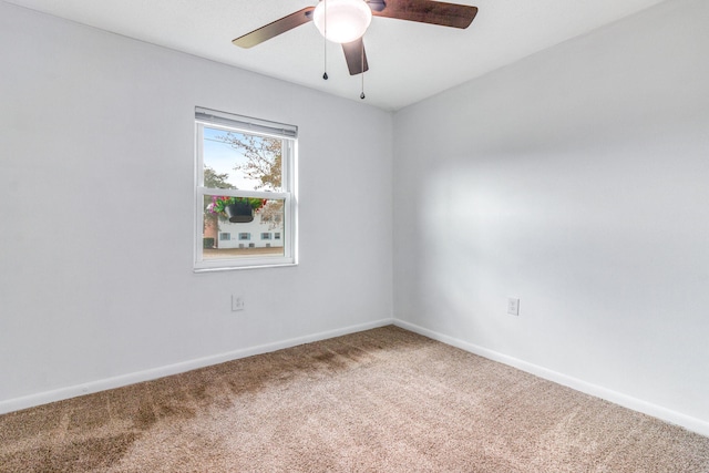 carpeted empty room with baseboards and a ceiling fan