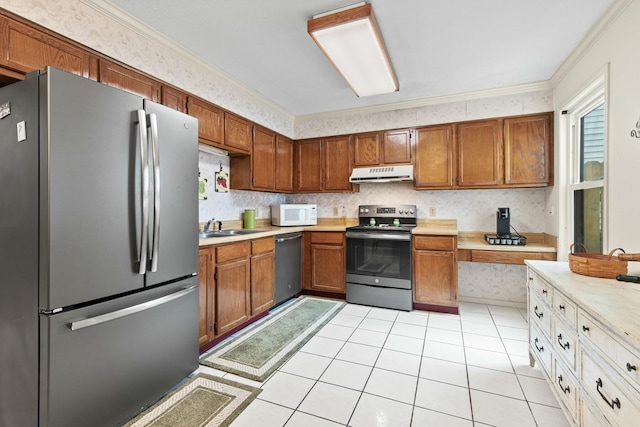 kitchen with light tile patterned flooring, ornamental molding, appliances with stainless steel finishes, and sink