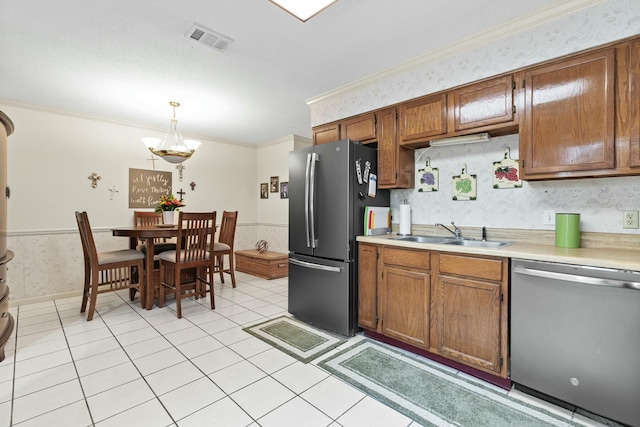 kitchen featuring sink, crown molding, decorative light fixtures, light tile patterned floors, and stainless steel appliances