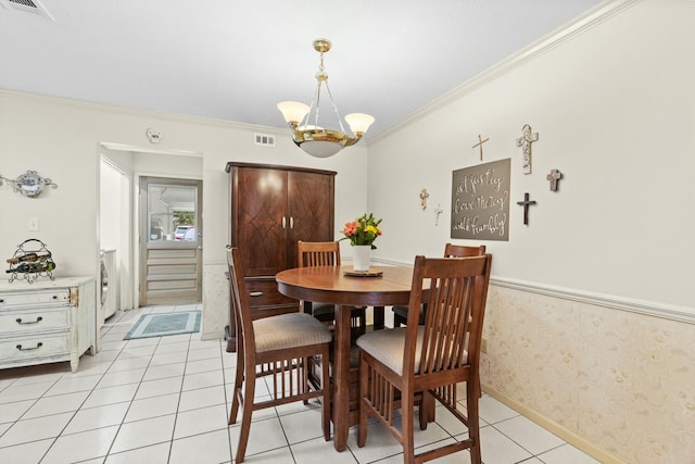 dining space featuring crown molding, light tile patterned flooring, and an inviting chandelier