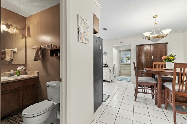 bathroom featuring tile patterned floors, toilet, an inviting chandelier, crown molding, and vanity