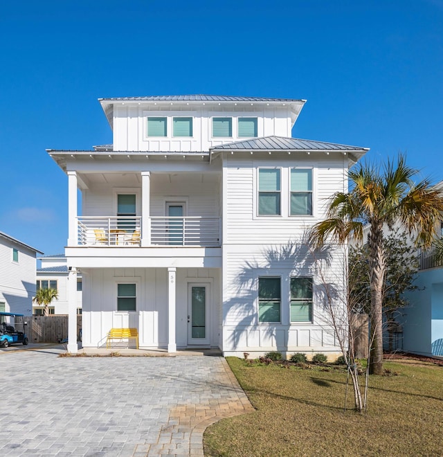 view of front facade with a balcony, a front yard, and covered porch