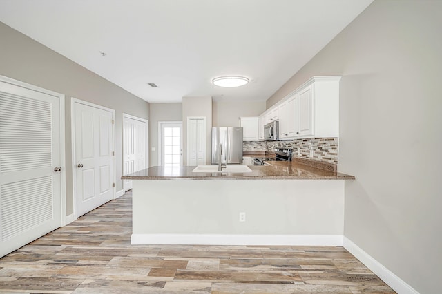 kitchen with stainless steel appliances, kitchen peninsula, light wood-type flooring, and white cabinets