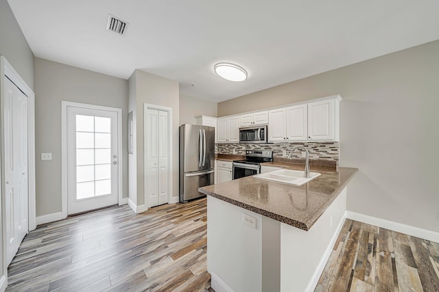 kitchen featuring sink, white cabinetry, backsplash, stainless steel appliances, and kitchen peninsula