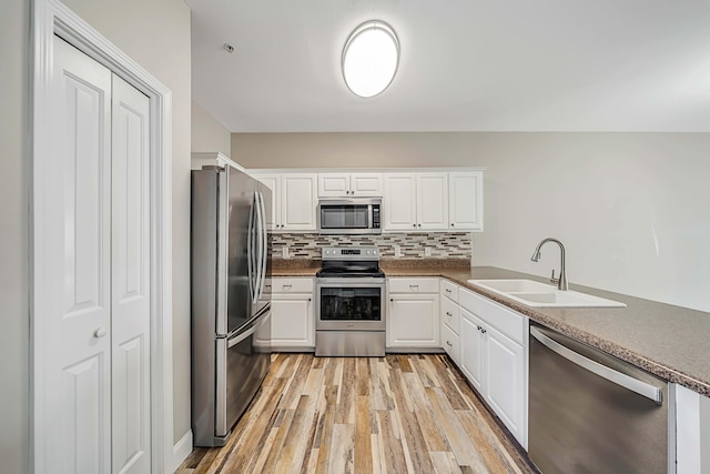 kitchen featuring stainless steel appliances, white cabinetry, sink, and light wood-type flooring