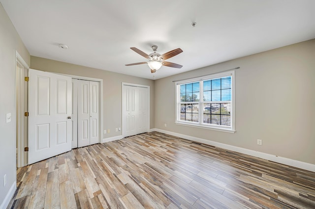 unfurnished bedroom with multiple closets, ceiling fan, and light hardwood / wood-style flooring