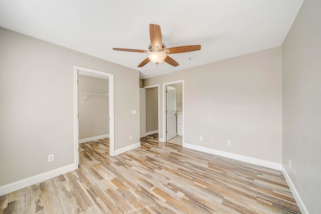 unfurnished bedroom with connected bathroom, light hardwood / wood-style flooring, a walk in closet, ceiling fan, and a closet