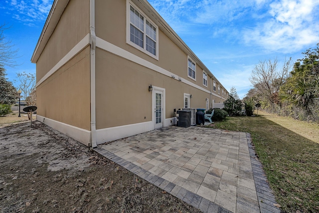 view of property exterior featuring central AC unit, a lawn, and a patio