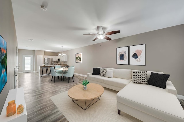 living room with ceiling fan with notable chandelier and hardwood / wood-style floors