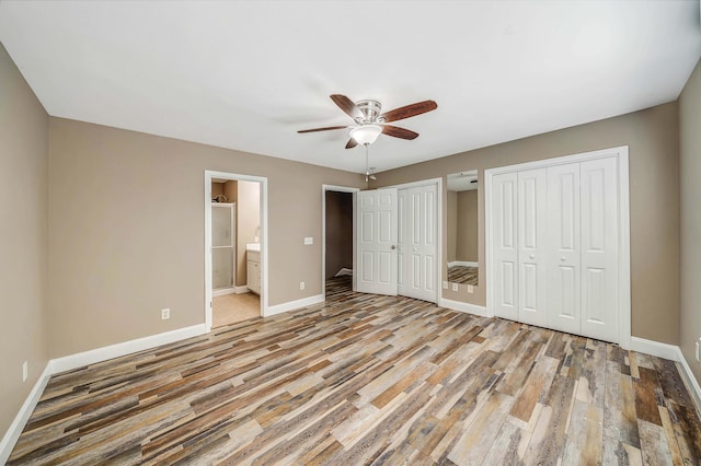 unfurnished bedroom featuring multiple closets, ceiling fan, connected bathroom, and light hardwood / wood-style floors