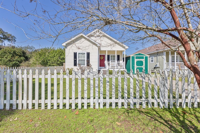 view of front of home featuring a storage shed, a front lawn, and covered porch