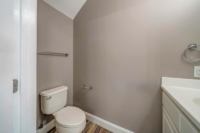 bathroom featuring hardwood / wood-style flooring, vanity, lofted ceiling, and toilet