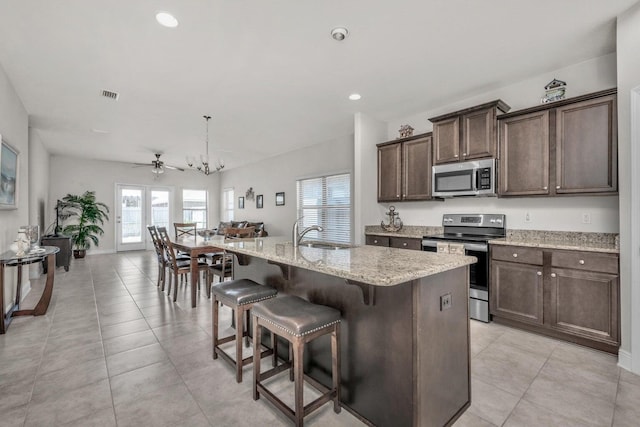 kitchen featuring appliances with stainless steel finishes, a breakfast bar, decorative light fixtures, sink, and a kitchen island with sink