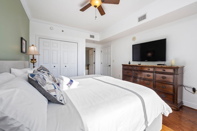 bedroom with hardwood / wood-style flooring, ornamental molding, ceiling fan, and a closet