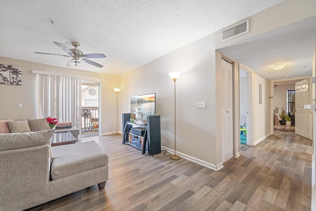 living area with baseboards, a textured ceiling, visible vents, and wood finished floors