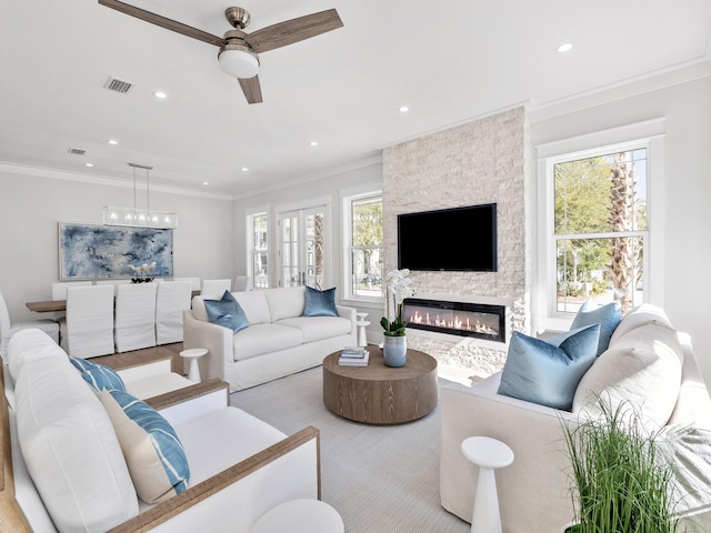 living area featuring a fireplace, visible vents, crown molding, and recessed lighting