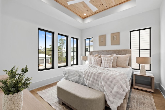 bedroom with a skylight, wooden ceiling, a raised ceiling, and light wood-type flooring