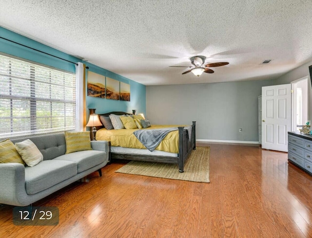 bedroom with hardwood / wood-style flooring, ceiling fan, and a textured ceiling