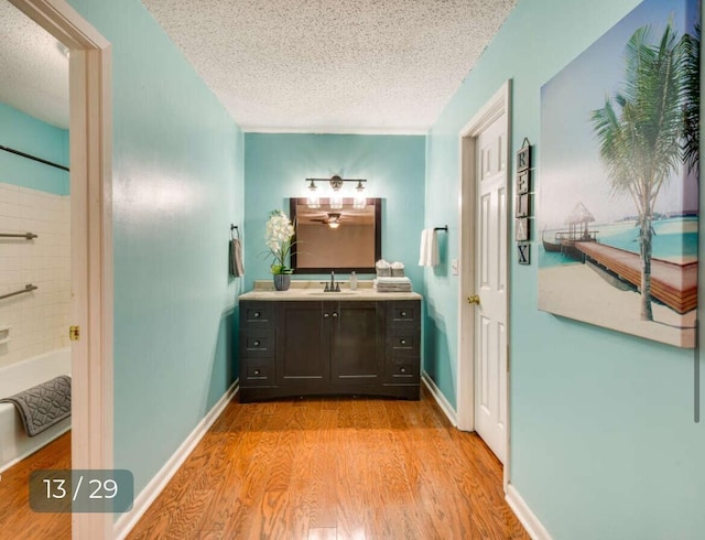 bathroom featuring washtub / shower combination, wood-type flooring, a textured ceiling, and vanity