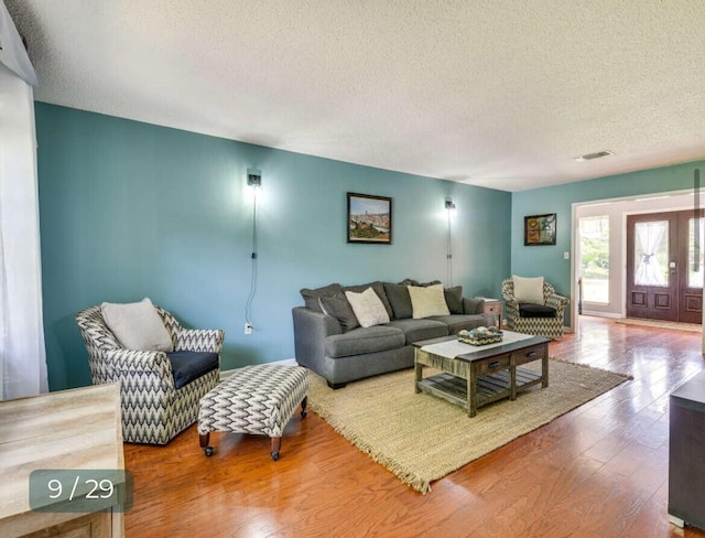 living room featuring hardwood / wood-style flooring, french doors, and a textured ceiling