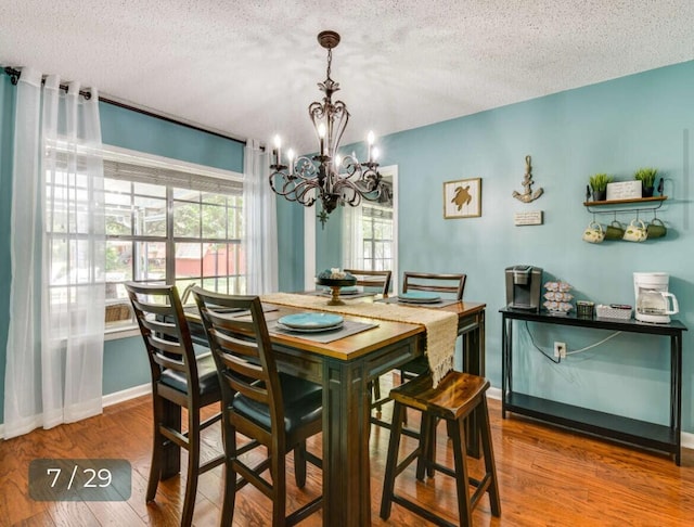 dining room with hardwood / wood-style floors, a notable chandelier, and a textured ceiling