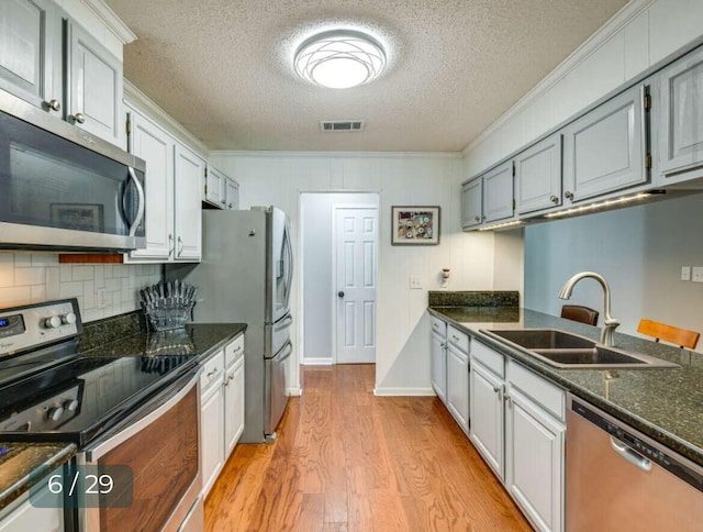 kitchen featuring ornamental molding, appliances with stainless steel finishes, sink, and light hardwood / wood-style floors