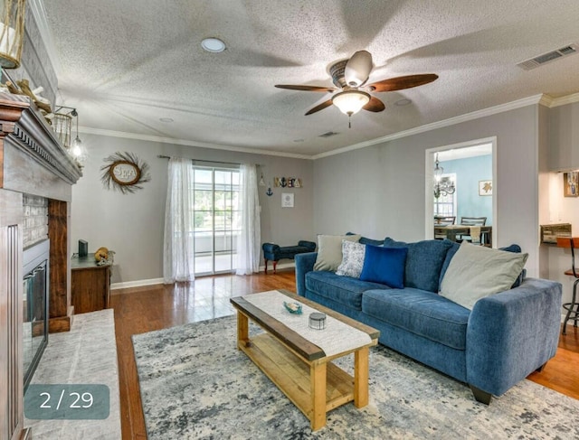 living room featuring hardwood / wood-style flooring, a fireplace, ornamental molding, and a textured ceiling