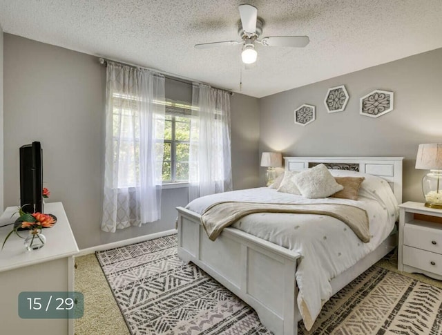 bedroom with light carpet, ceiling fan, and a textured ceiling