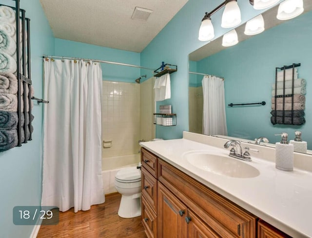 full bathroom with toilet, a textured ceiling, vanity, shower / bath combo with shower curtain, and hardwood / wood-style floors