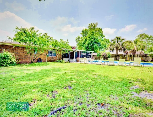 view of yard featuring a fenced in pool and a sunroom