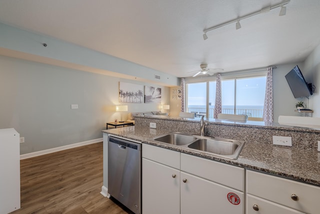 kitchen featuring sink, dark stone countertops, white cabinets, stainless steel dishwasher, and dark wood-type flooring