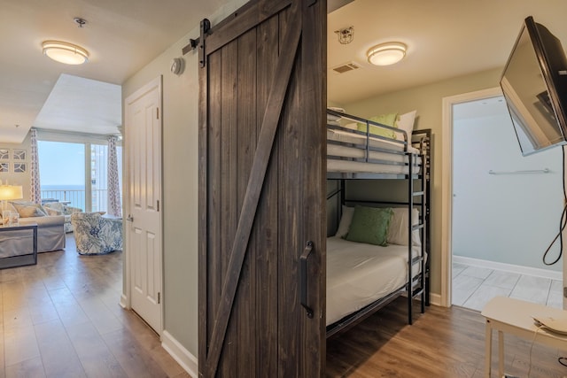 bedroom featuring wood-type flooring and a barn door