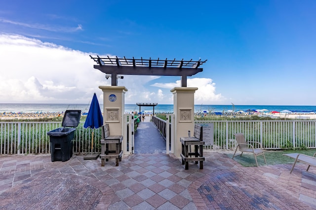 view of patio with a water view, a view of the beach, and a pergola