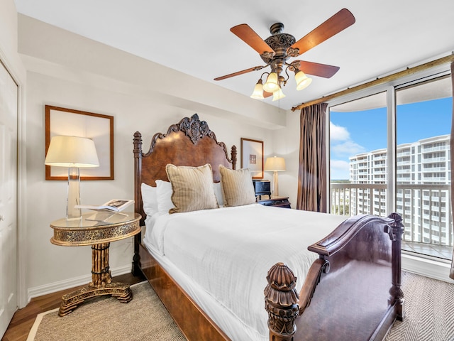 bedroom with wood finished floors, a ceiling fan, baseboards, access to outside, and a view of city