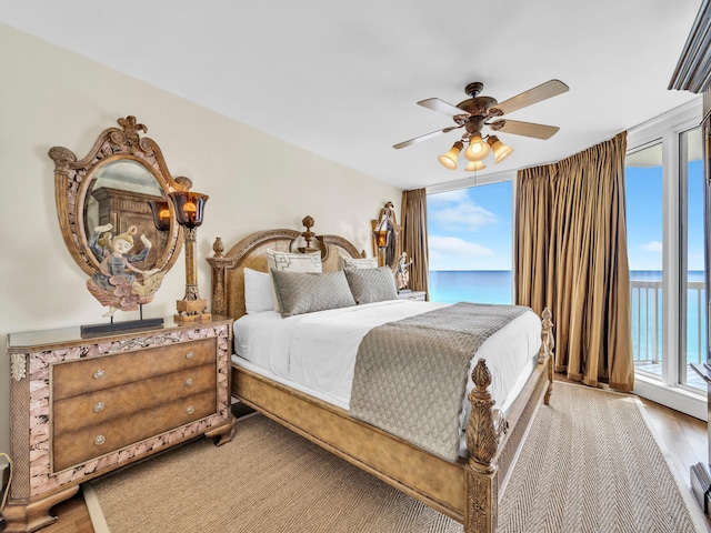 bedroom featuring wood finished floors, a water view, and multiple windows