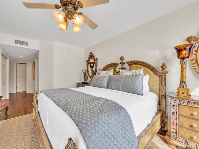 bedroom featuring a ceiling fan, visible vents, and wood finished floors