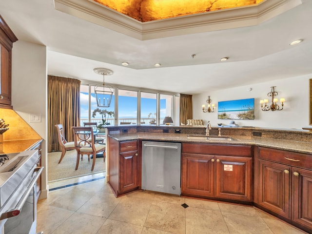 kitchen with a tray ceiling, pendant lighting, stove, a sink, and dishwasher