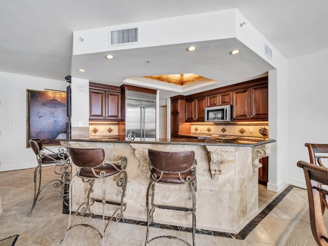 kitchen featuring appliances with stainless steel finishes, a raised ceiling, visible vents, and baseboards