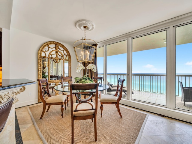 dining room with a chandelier, a water view, and baseboards