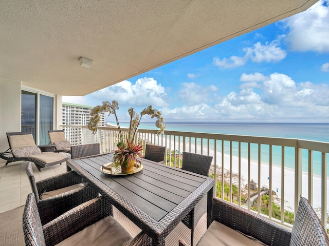 balcony with outdoor dining space, a beach view, a sunroom, and a water view