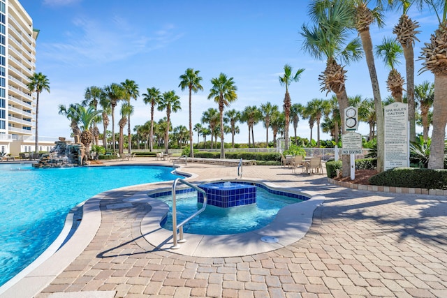 community pool with a patio area and a hot tub