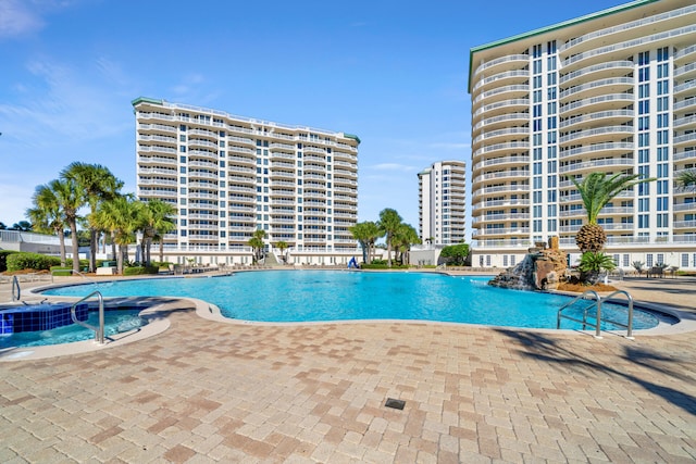 pool with a patio area, a hot tub, and a city view